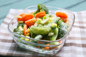 Bowl with different frozen vegetables on color wooden background, closeup