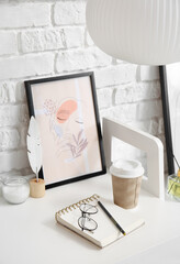 Stylish workspace with modern painting in frame near brick wall, closeup