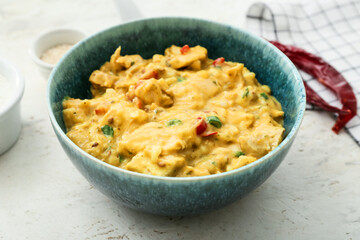 Bowl of tasty chicken curry on light background
