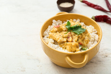 Pot of tasty chicken curry with rice on light background