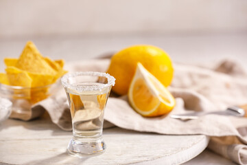 Shot of tasty tequila with lemon on table, closeup