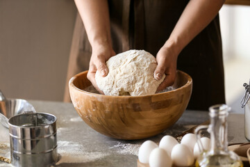 Female chef preparing dough on kitchen table, closeup