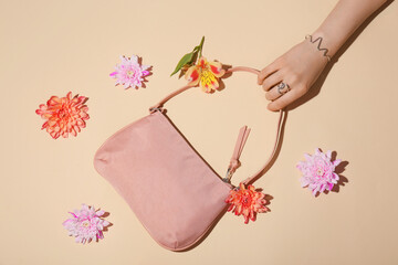 Female hand with stylish accessories and bag on color background