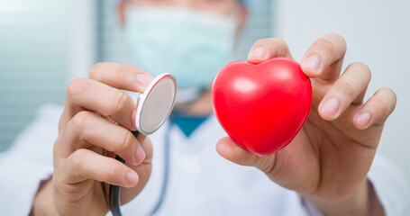 A doctor is holding and showing a red heart. Concept for topics: health, support, international or national cardiology day. Close up of man hands with heart