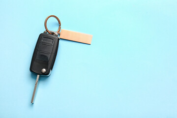 Car key with stylish keychain on color background