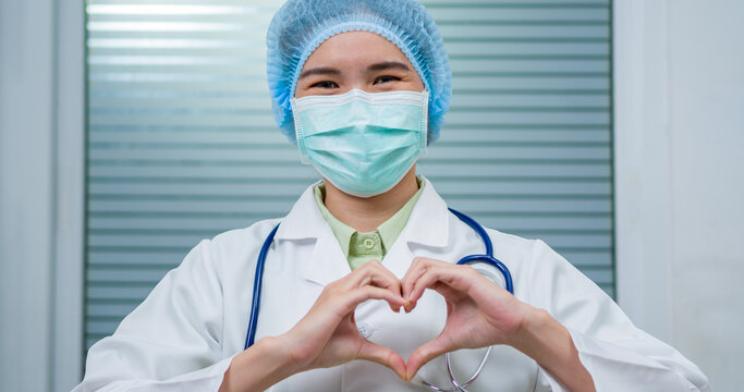 Young doctor woman, medical professional happy showing love with hands in heart shape expressing healthy and marriage symbol. Close up of man hands with heart. Romantic concept.