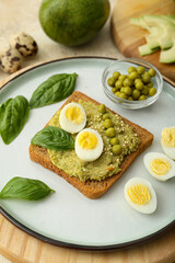 Tasty sandwich with guacamole, eggs and peas on color background, closeup
