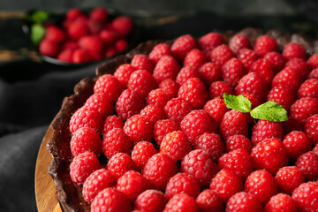 Board with tasty raspberry pie and mint on table, closeup
