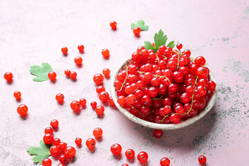 Bowl with fresh red currants and leaves on color background, closeup