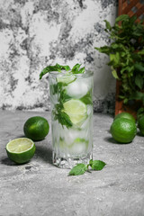 Glass of fresh mojito, limes and mint on grunge background