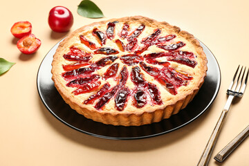 Plate with tasty plum pie on color background, closeup