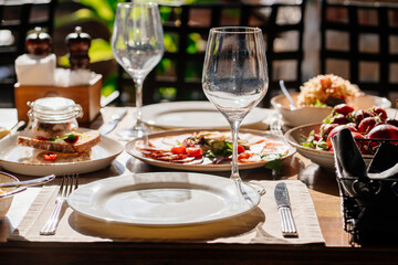 wooden table served with plates with salad and snacks on the open terrace
