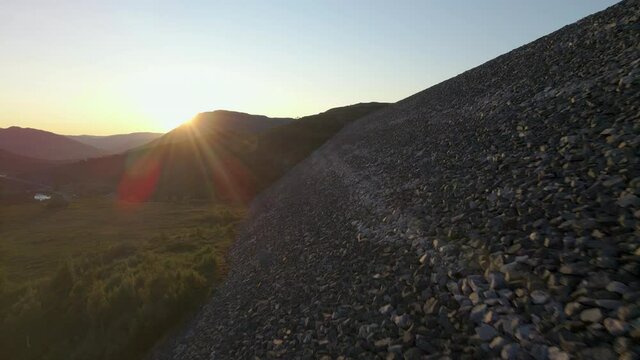 Bright Yellow Sunlight Shining Over The Mountain From Rock-fill Embankment Of Sysen Dam In Norway. - aerial