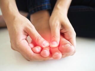 Foot pain, woman hand holding a sore foot on white background. closeup photo, blurred.