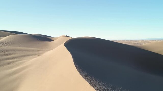 Aerial drone flight over sand dunes in the desert showing various textures