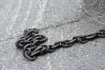 A large, long chain against the backdrop of the sidewalk. Close-up 