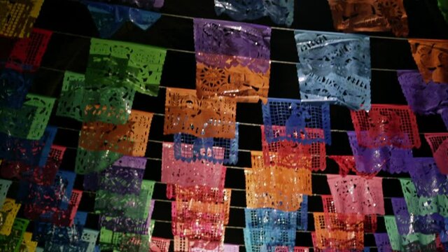 Panning down street filled with Papel Picado perforated paper at night time