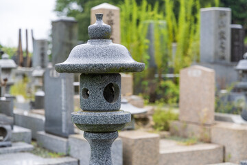 Fototapeta na wymiar 雨の日の墓地の石灯籠と墓石