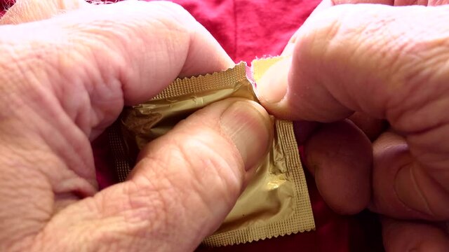 A man unrolls a condom from a package