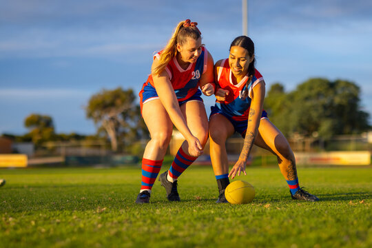 two aussie rules football players going for the ball