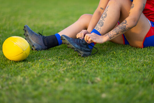 detail of footballer sitting on grass tying bootlace