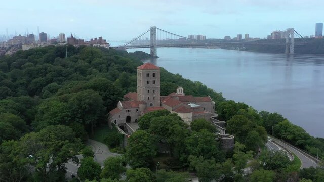 CCW aerial orbit that pulls away from The Cloisters atop a hill in Upper Manhattan NYC.  Views of the George Washington Bridge over the Hudson River in the distance.