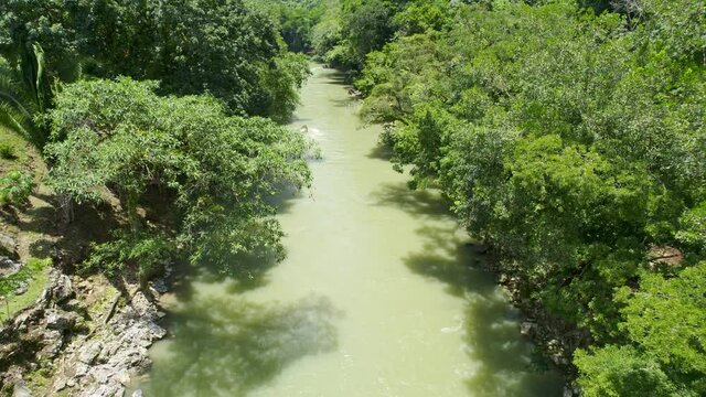 Drone aerial footage of flowing rainforest river lined with lush green trees and foliage. Rio Cahabon, Guatemala near Semuc Champey National Park.