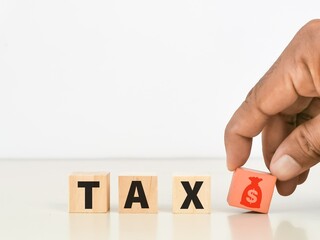 Tax and finance concept. Tax with money bag on wooden cubes with hand.