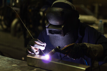 Skillful welders weld steel in the factory. Construction site metal welder. builder wear fireproof gloves for safety at work.