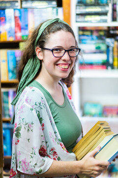 portrait of young woman shopping for second hand books in a store