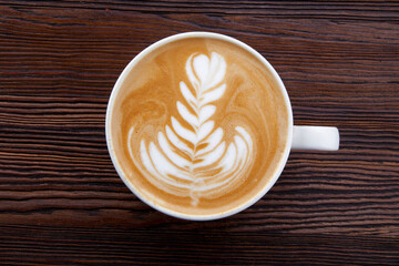cup of hot cappuccino with pattern on wooden background
