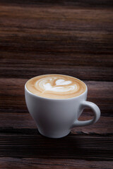 cup of hot cappuccino with pattern on wooden background
