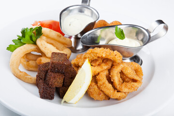plate with beer snacks, fried croutons, squid, onions and sauces