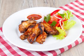 grilled chicken wings with tomato spicy sauce and tomatoes with herbs