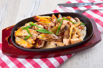Italian frying pan with potatoes, meat and mushrooms in mushroom sauce