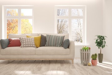 Stylish room in white color with sofa and autumn and winter landscape in window. Scandinavian interior design. 3D illustration
