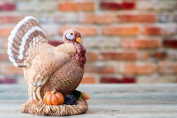 Vintage clay turkey against a brick wall. Seasonal display for Thanksgiving and Halloween.