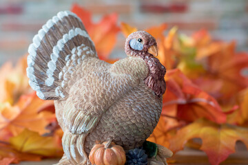 Vintage clay turkey with colorful autumn leaves. Seasonal display for Thanksgiving and Halloween.