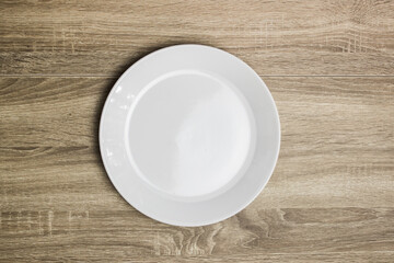 An empty white plate on wooden table