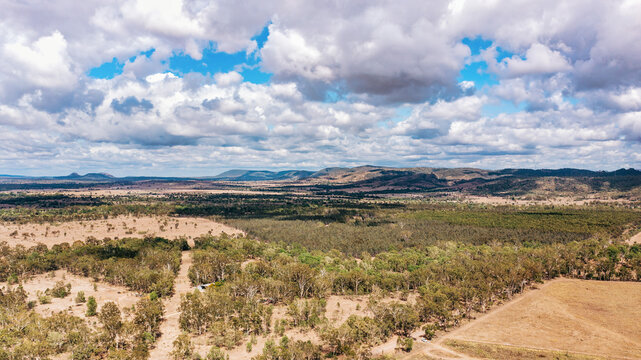 Horizontal shot of a dry landscape with trees and mountains on a cloudy sky