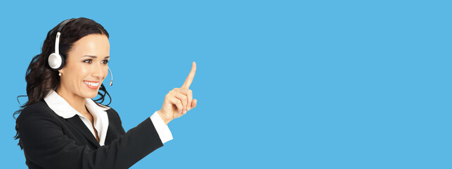 Call center service. Portrait of customer support phone sales operator in headset showing pointing at copy space area for text, imaginary, product or slogan, over bright blue background.