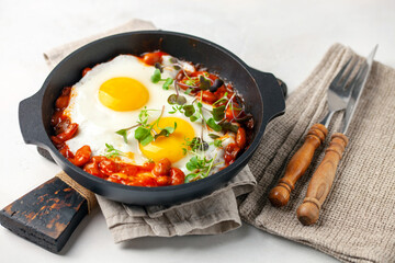 Continental breakfast - fried eggs and beans in tomato sauce in a serving pan on the table