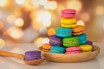 Delicious macaroons, a famous multicoloured French dessert stacked on a wooden plate. Selective focus. Blurred background