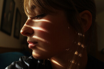 Close up dramatic light and shadows fall on attractive woman's face profile