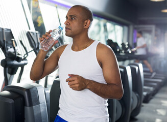Positive man with bottle of water in a sports club