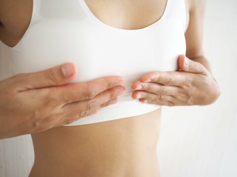 Small breast problem a woman wearing exercise clothes or white underwear. hands holding on chest. Breast augmentation concept. closeup photo, blurred.