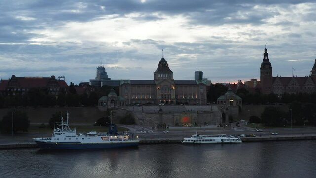 Ferry Services Docked On The Side Of Oder River At Twilight With National Museum Of Szczecin In Background. Chrobry Embankment In Poland. wide drone shot