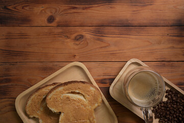 Delicious toasts with peanut butter and cup of hot coffee on wooden background.