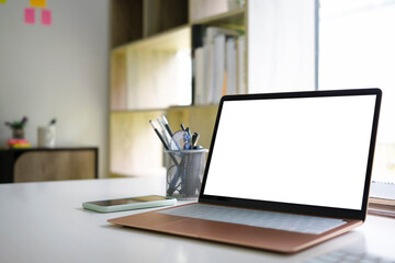 Mock up laptop computer, smart phone and pencil holder on white office desk.