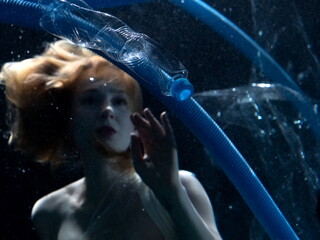 Woman swimming underwater among plastic trash. Girl drowning in sea among garbage. Ecology problem...